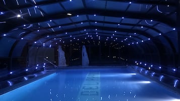 Una piscina interior con techo de cristal y varias luces.