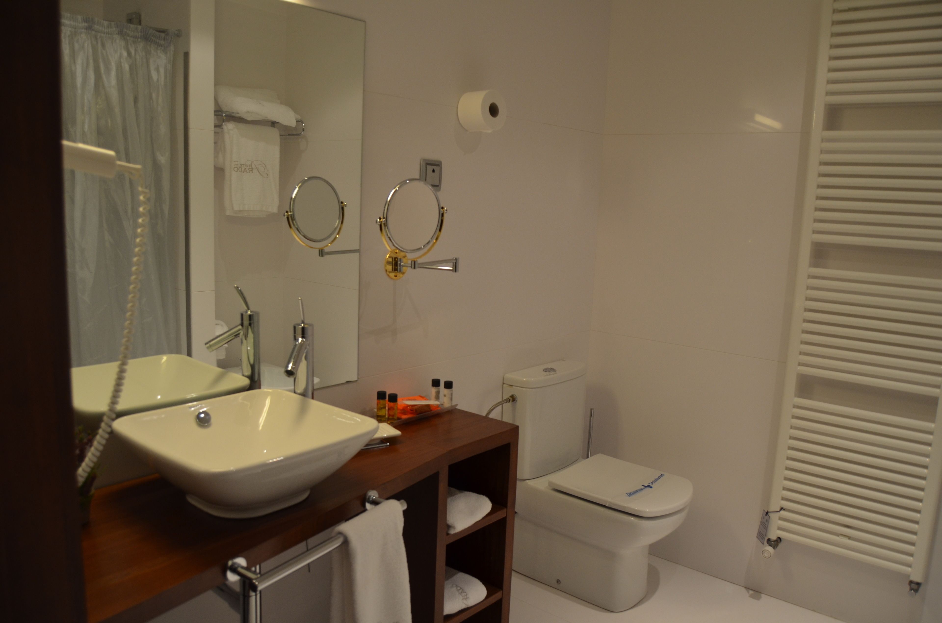 Un baño con lavamanos, espejo, inodoro y toallero.