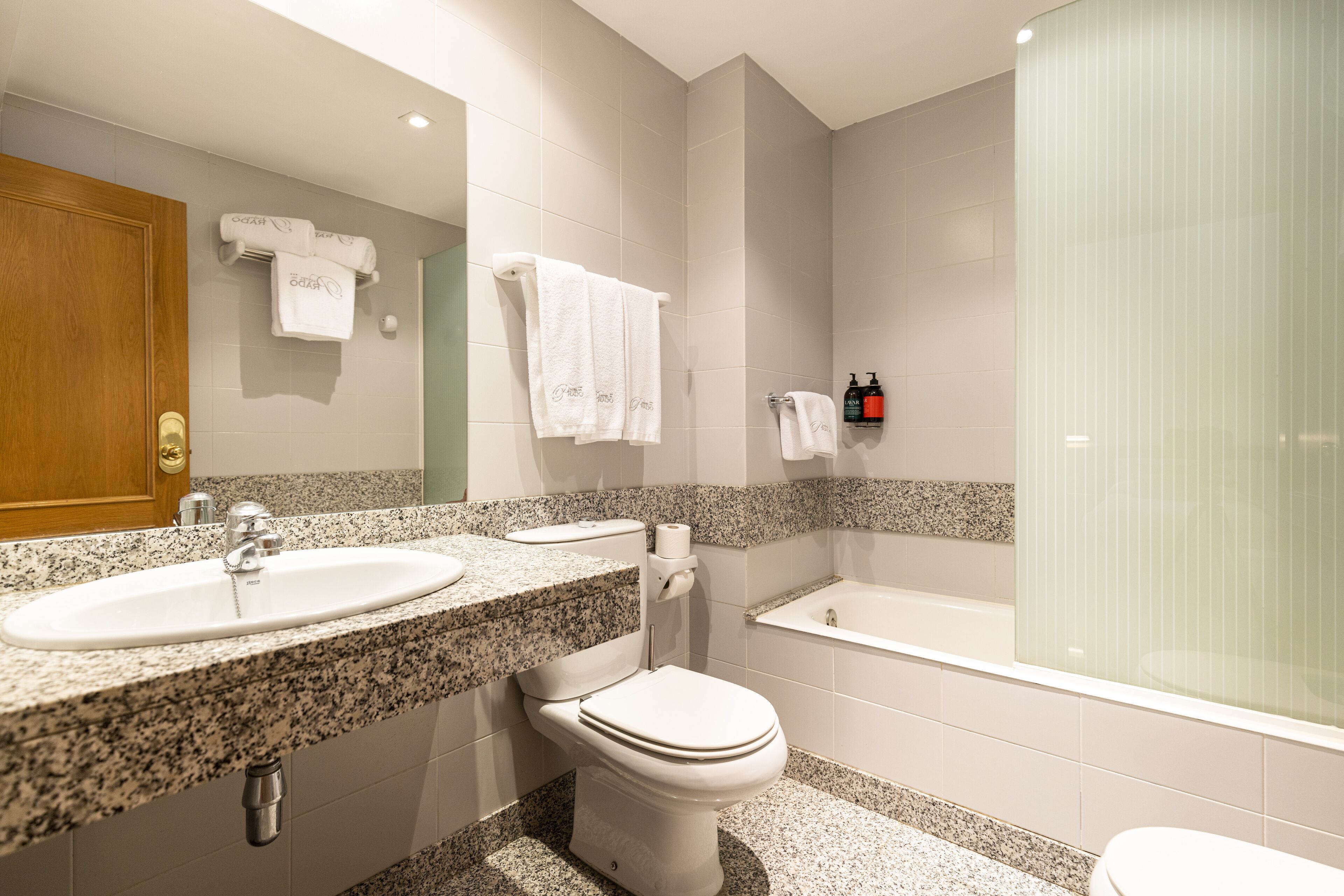 Une salle de bain moderne avec un lavabo surmonté d’un plan en granit, des toilettes et une baignoire.