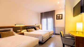 Een hotelkamer met twee bedden, een bureau, een stoel, een televisie en een raam met gordijnen.