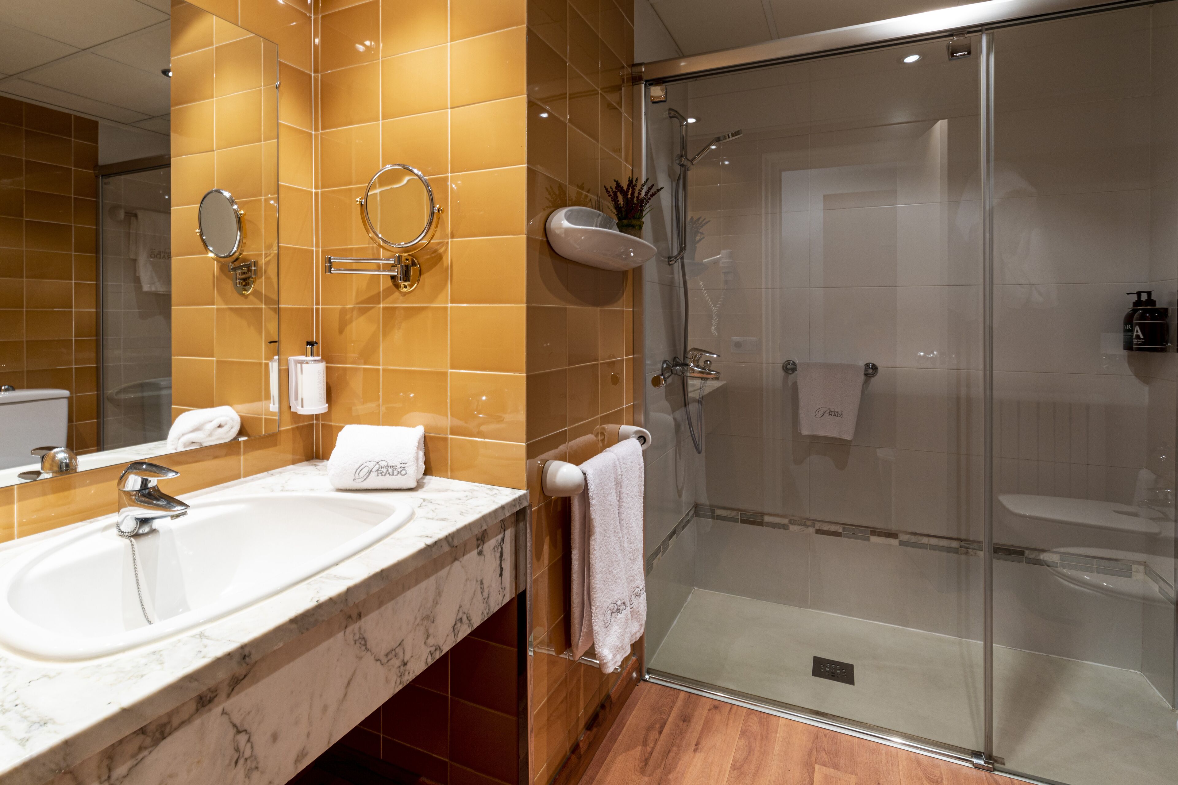 Un baño con un lavabo grande, espejo y ducha con mampara de vidrio.