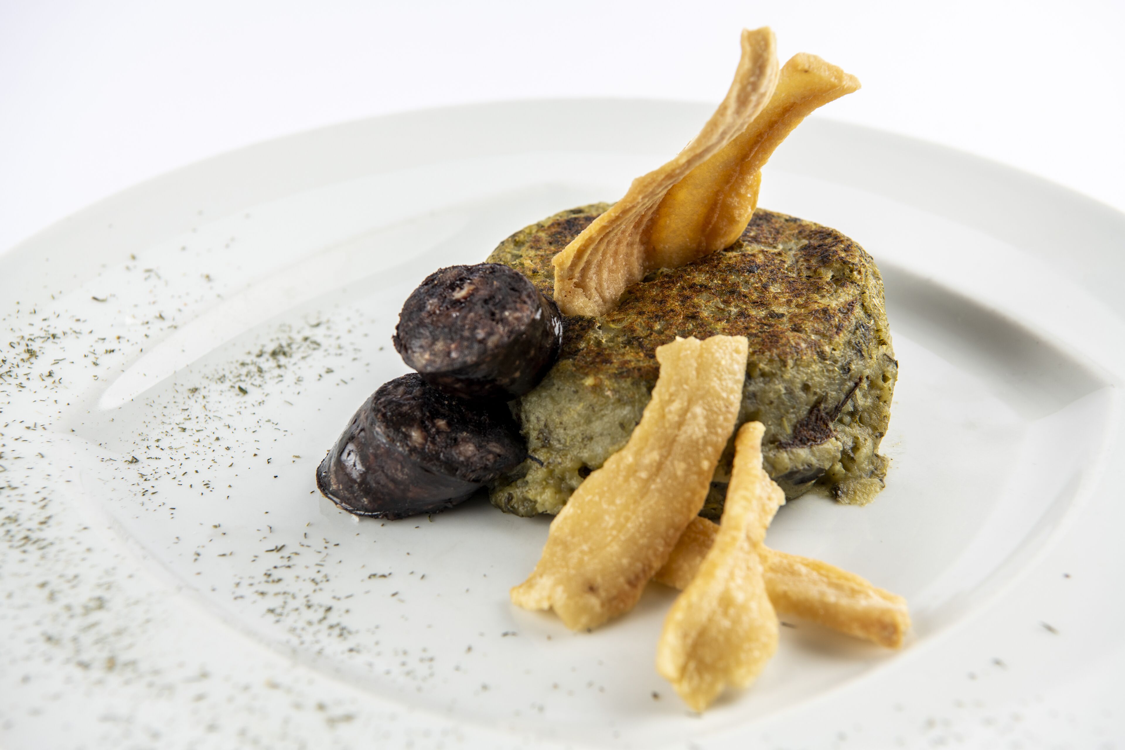 Une assiette comprenant une galette de viande, deux saucisses et deux aliments frits.