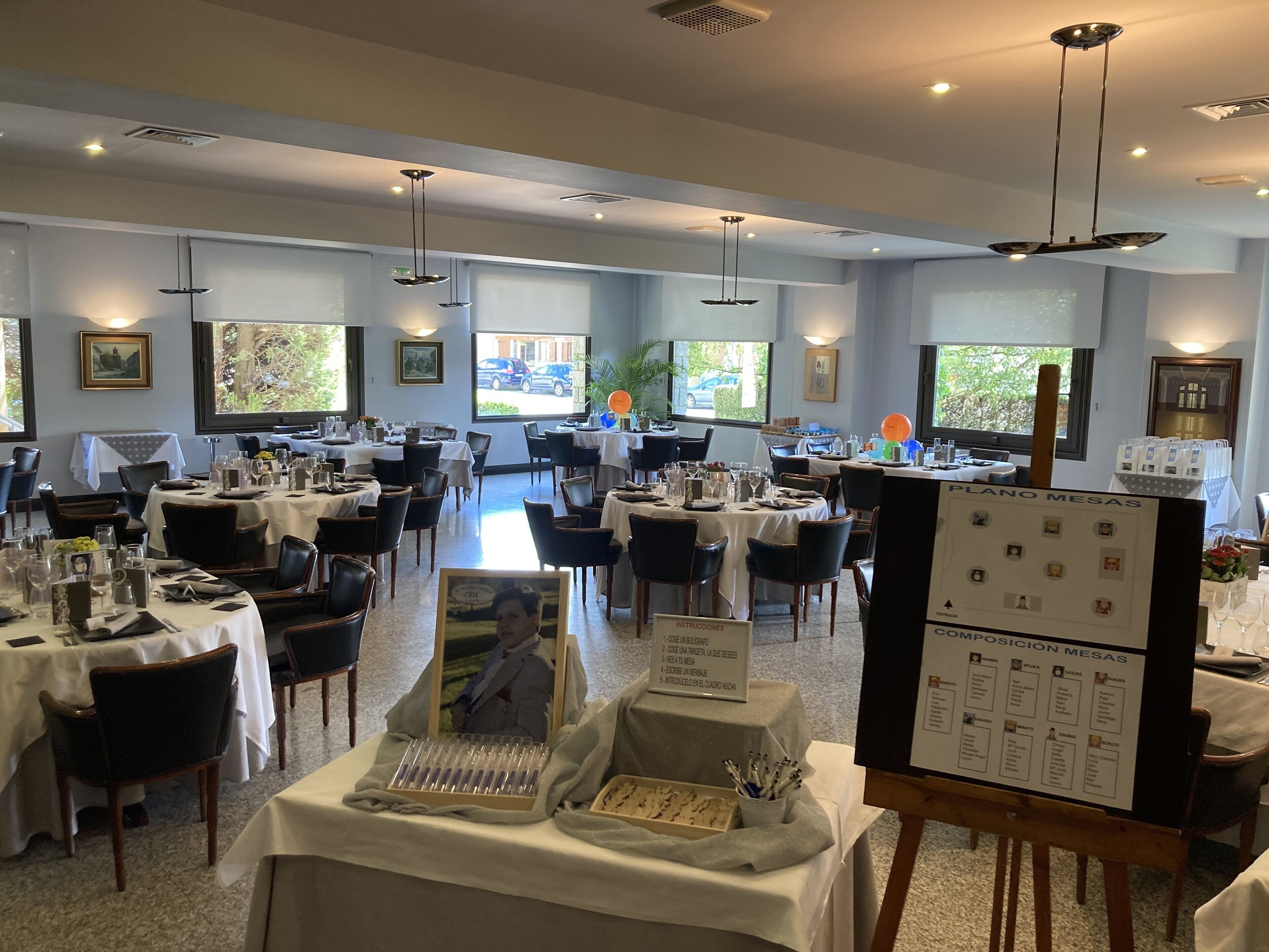 Un espace repas avec des tables dressées, un tableau affichant le menu et des tableaux encadrés accrochés aux murs.