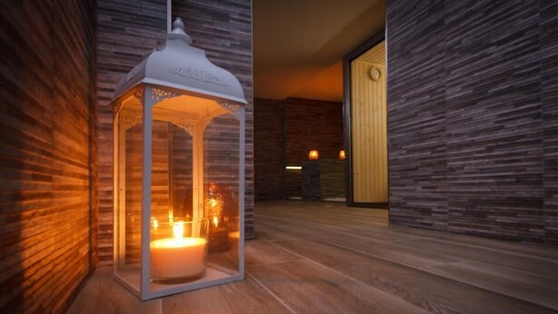 A modern interior with a wooden floor, a white lantern with a candle, and a stone wall. - Hotel Eth Solan (Vielha e Mijaran)