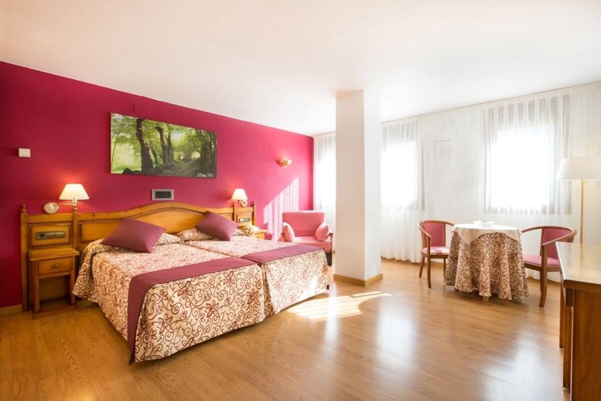 Un dormitorio con cama, mesitas de noche, un escritorio y una silla.