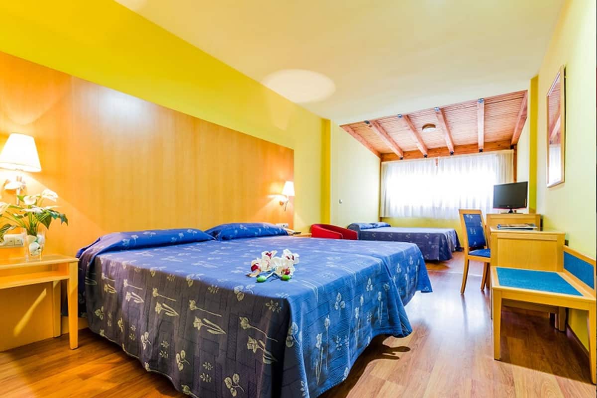 Een hotelkamer met twee bedden, een bureau, een stoel en een televisie.