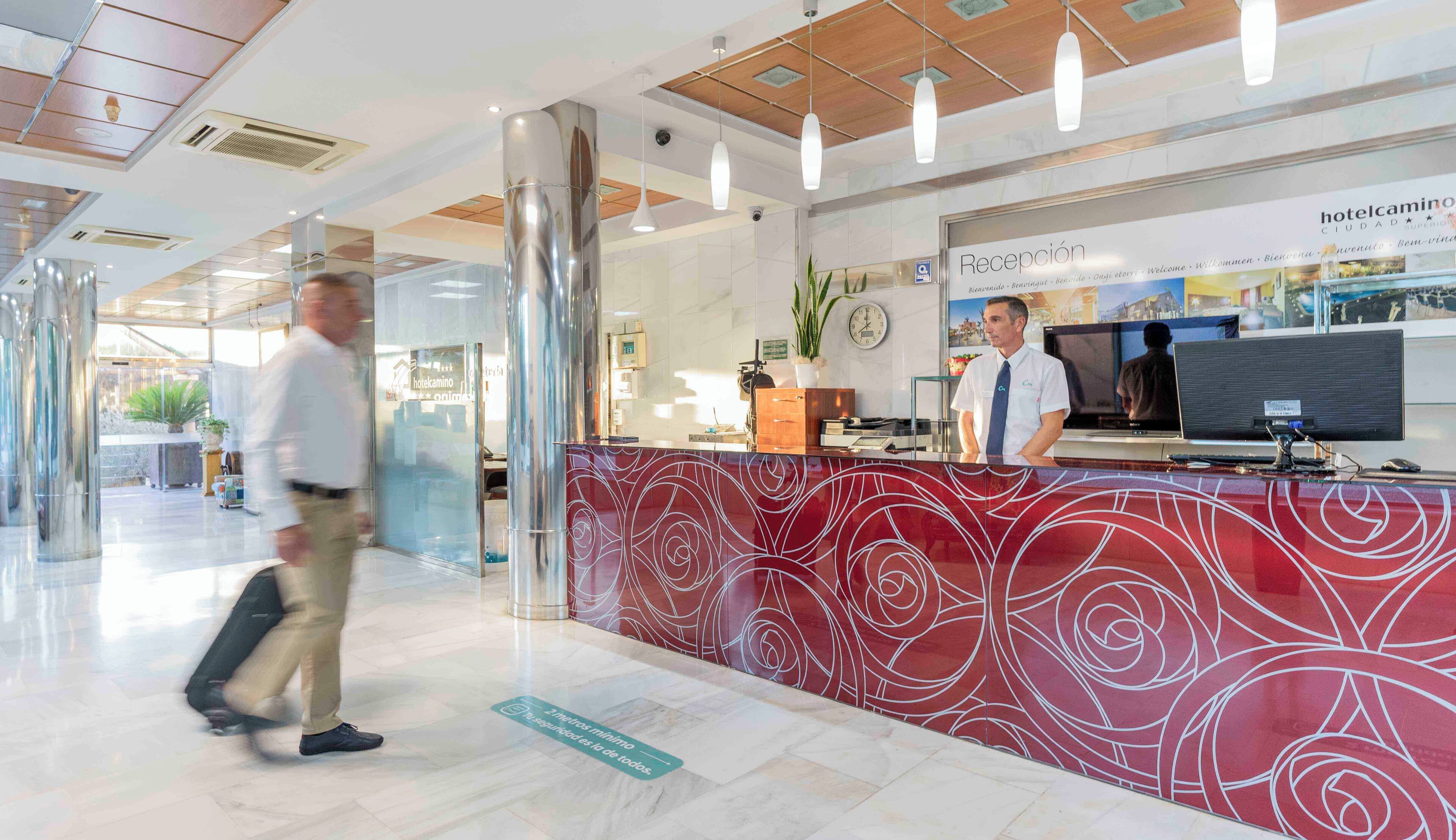 A hotel reception area with a modern design, including a reception desk, a digital screen, and a clock.