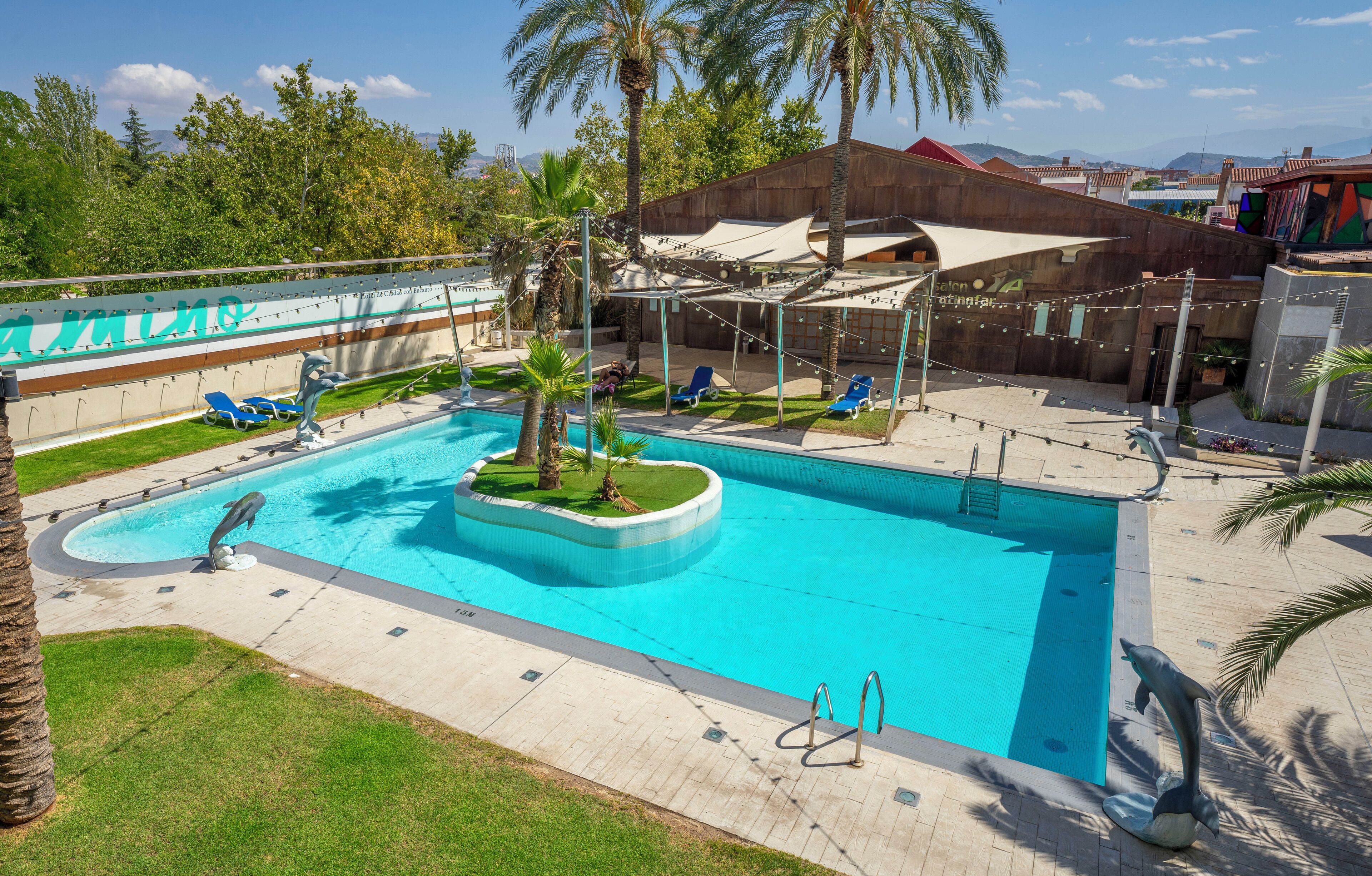 Una piscina con estatuas de delfines, sillas de descanso y palmeras.