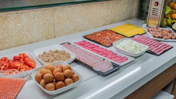 A buffet with various food items including sliced tomatoes, eggs, and different types of meat.