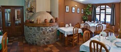 A restaurant with stone walls, wooden tables, and chairs.