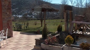 Un patio con piso de ladrillo, una estructura de techo de paja y un jardín con diversas plantas.