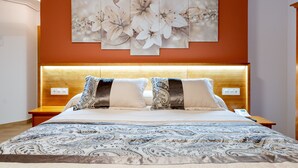 Una cama bien tendida con una colcha estampada, un cabecero de madera y una obra de arte floral en la pared sobre ella.