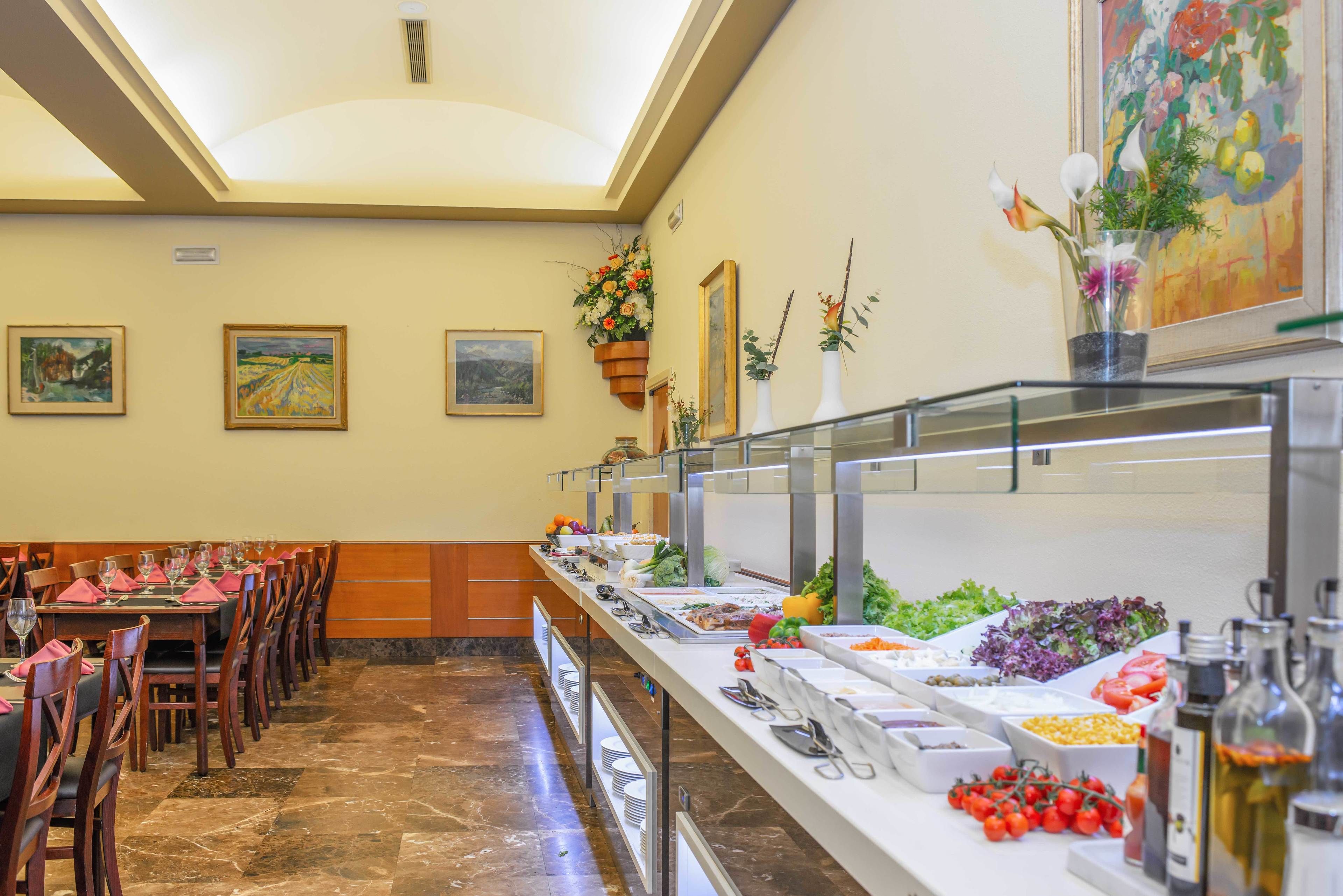 A buffet setup with various food items and a dining area with tables and chairs.