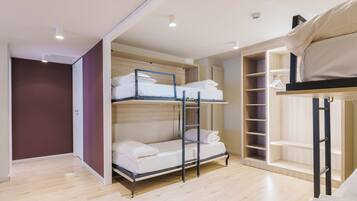 A bunk bed room with a wooden floor, a wardrobe with hanging space, and a ceiling light.