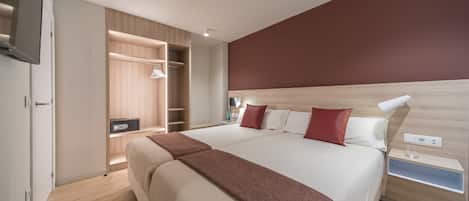 Una habitación de hotel moderna con una cama grande, armario de madera y televisor integrado.