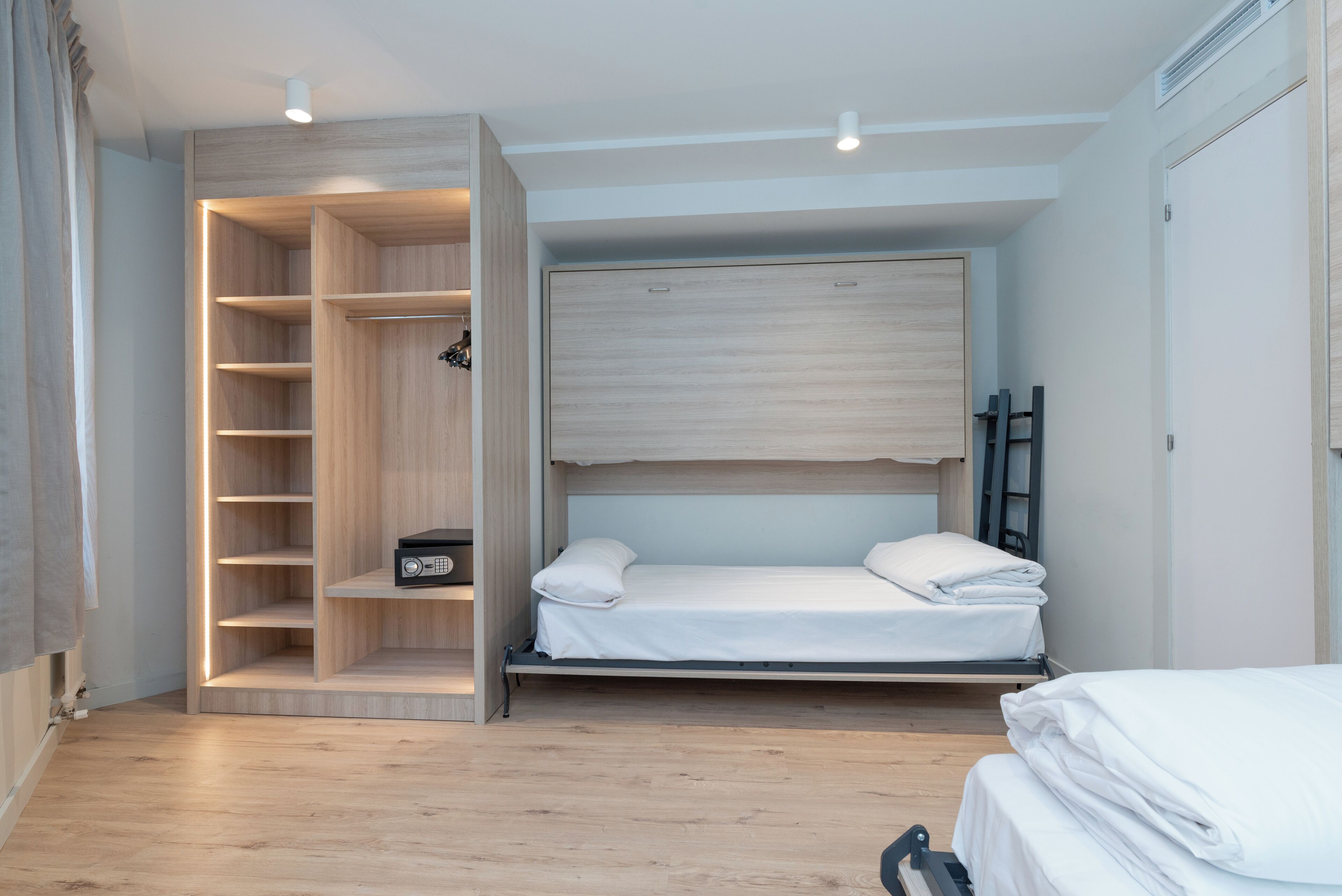 Une chambre à coucher de taille réduite, comprenant un lit, une armoire intégrée et une table de chevet.