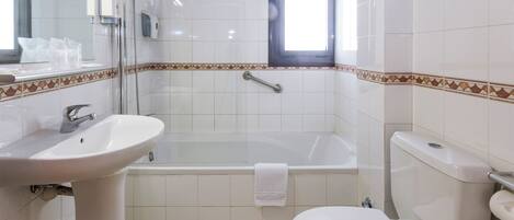 A bathroom with a bathtub, toilet, sink, and a window.