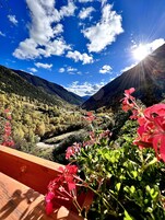 Paisaje montañoso con un valle y una baranda de madera en primer plano.