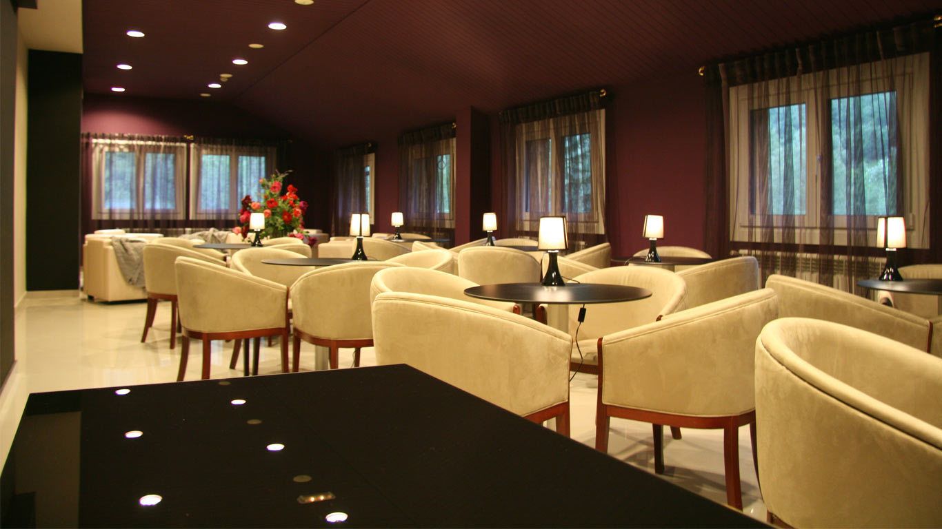 A hotel lobby with multiple seating areas, including sofas and armchairs, arranged around a central table.