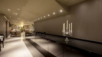 Een moderne, goed verlichte hotellobby met een lange receptiebalie, zithoek en een kroonluchter.
