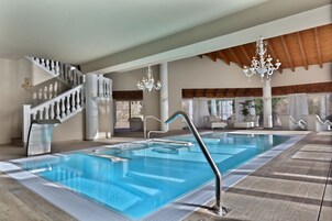 Una piscina con diseño moderno, una escalera con barandilla blanca y un candelabro.