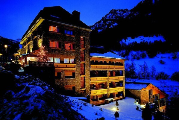 A multi-story hotel with a stone facade, multiple balconies, and a snow-covered surrounding. - Hotel & SPA Bringué (El Serrat)