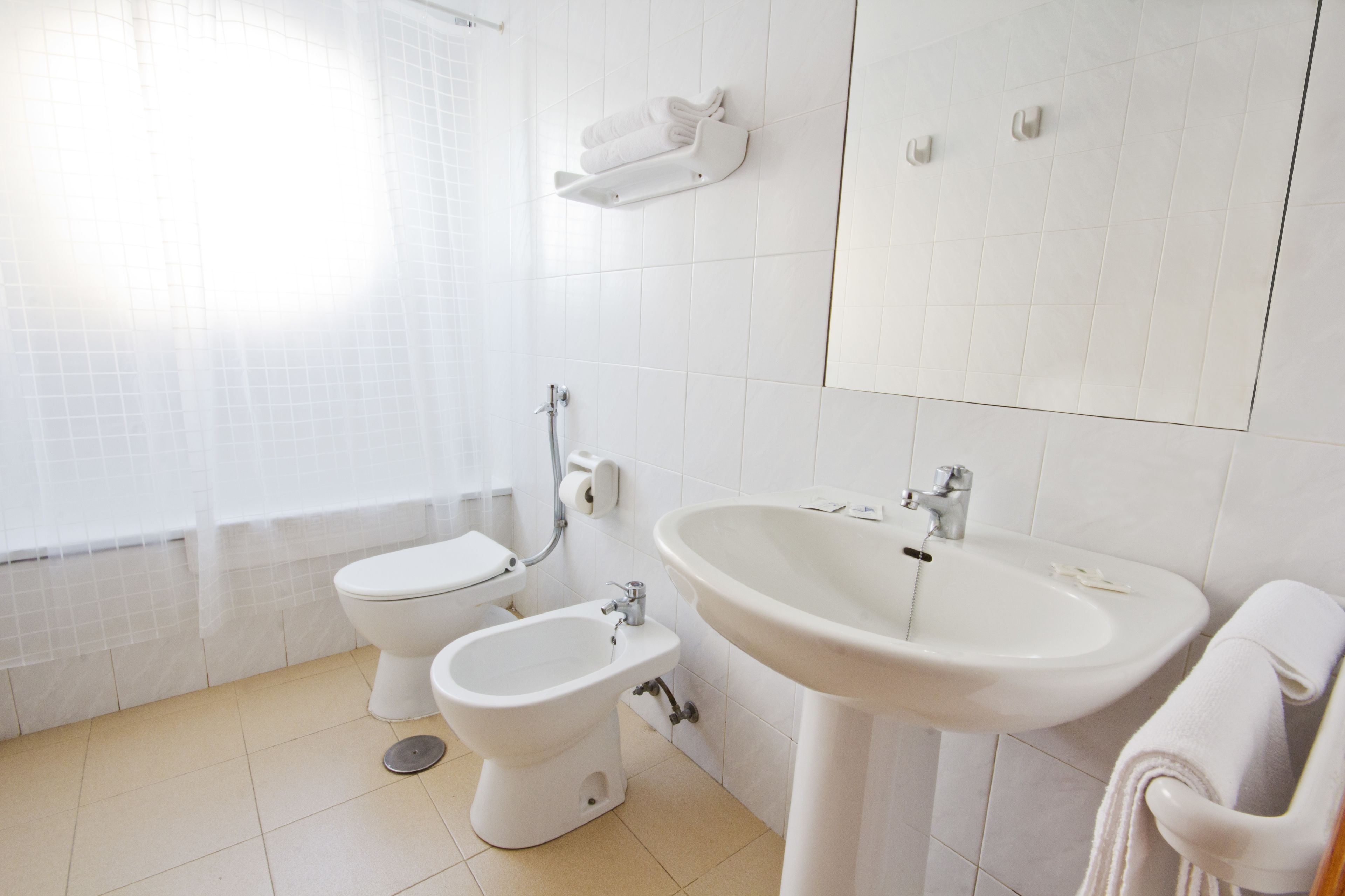 Une salle de bain équipée de toilettes, d’un bidet, d’un lavabo et d’un porte-serviettes.
