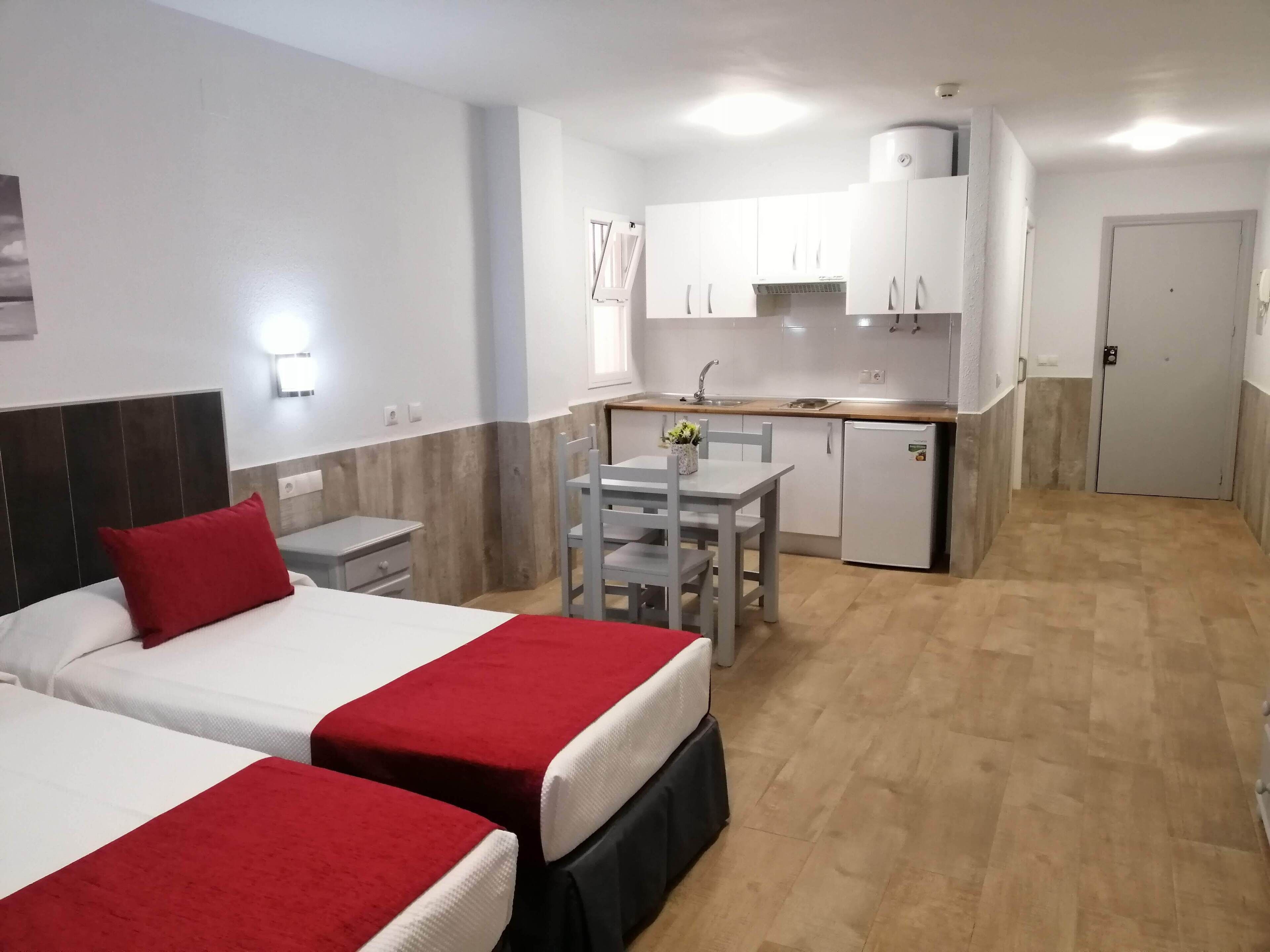 Una habitación de hotel con dos camas, una kitchenette y una zona de comedor.