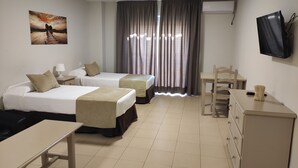 Une chambre d’hôtel avec deux lits, un bureau, une chaise, une télévision et un tableau au mur.
