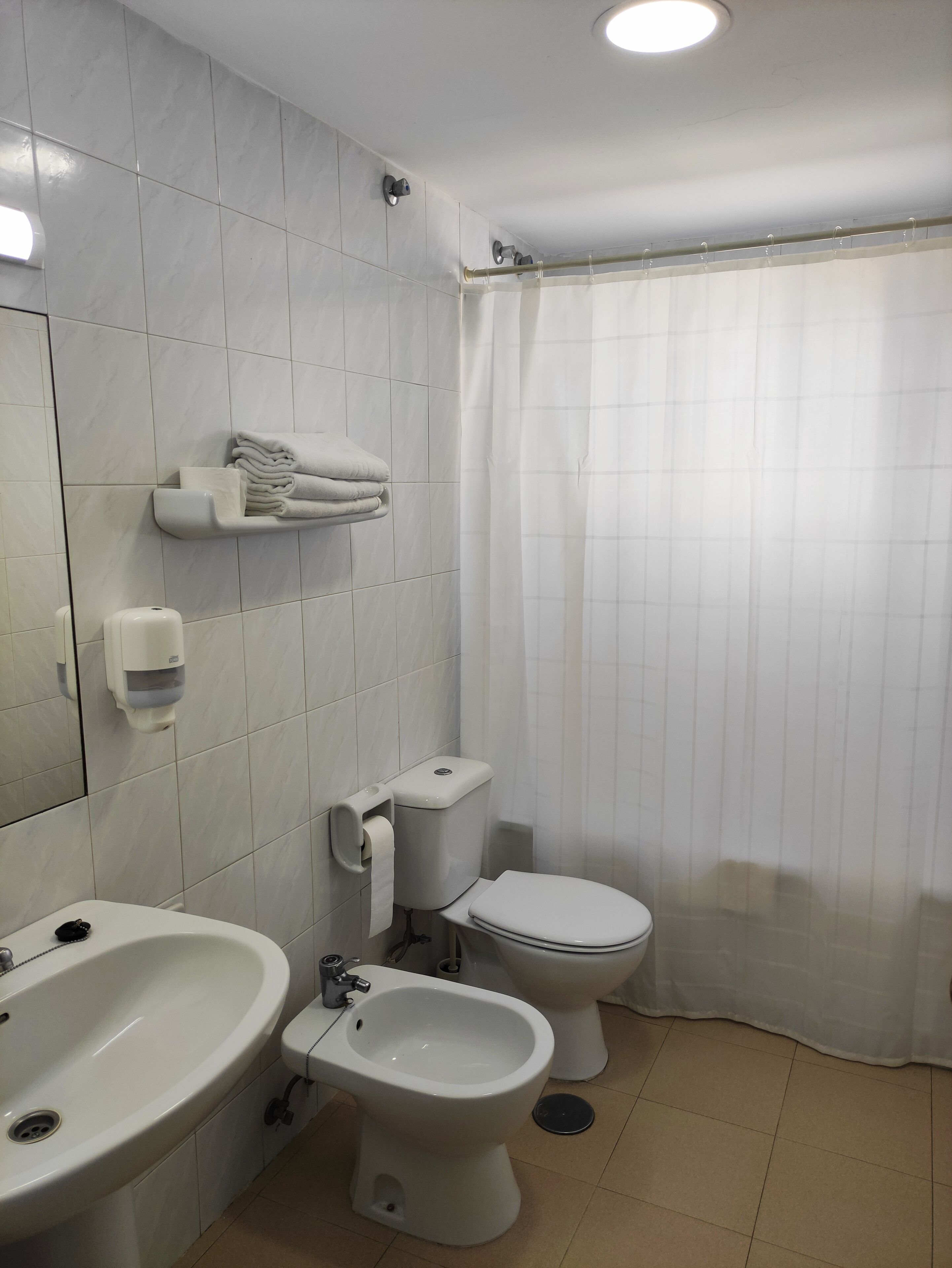 Baño con lavamanos, bidé, inodoro y toallero.