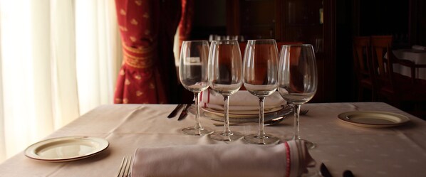 Mesa puesta con copas de vino, platos y cubiertos, indicando una disposición para comer.