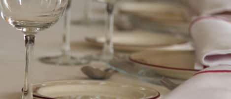 Mesa servida para cenar con varias copas de vino, platos y cubiertos.