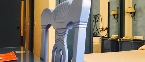 Habitación de hotel con cama, escritorio con silla, teléfono y espejo.