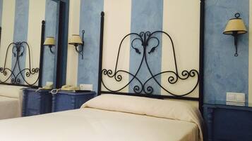 Una habitación de hotel con una cama, dos mesitas de noche, un espejo y lámparas de pared.