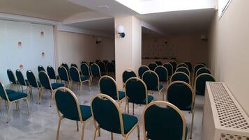 Ein Konferenzraum mit Reihen von türkisfarbenen Stühlen und einem weißen Tisch.