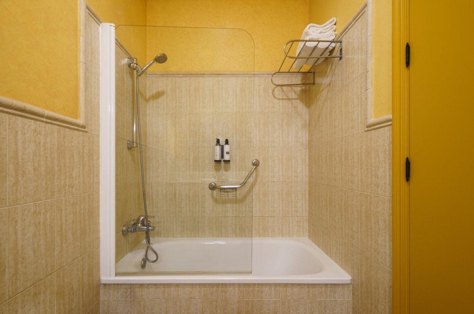 Een badkamer met een bad, een douche en een handdoekrek.