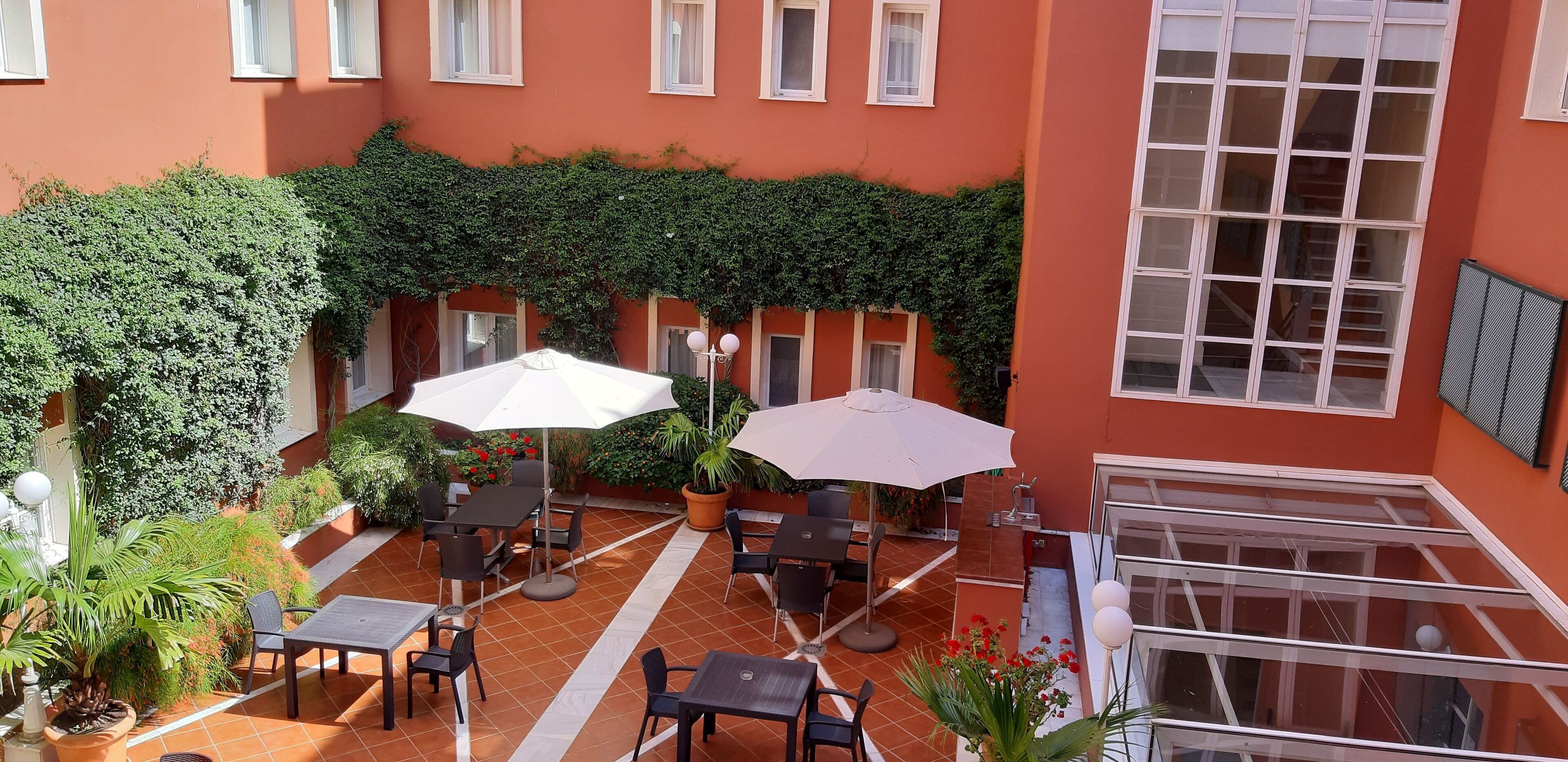 Une cour avec des espaces de détente en plein air, des plantes en pot et une balustrade en verre.