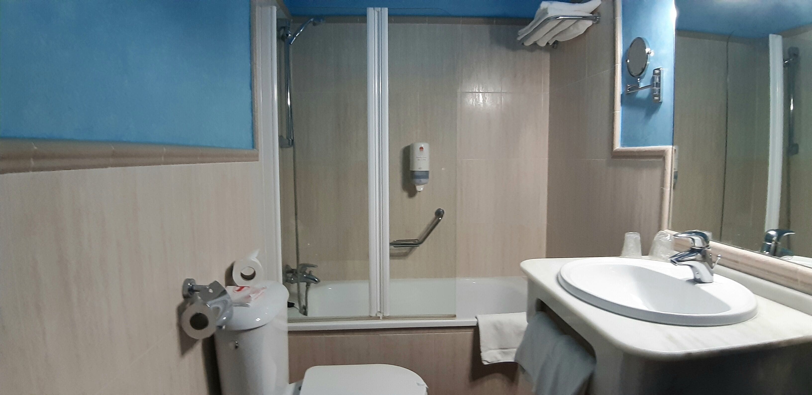 A bathroom with a shower, toilet, sink, and a mirror.