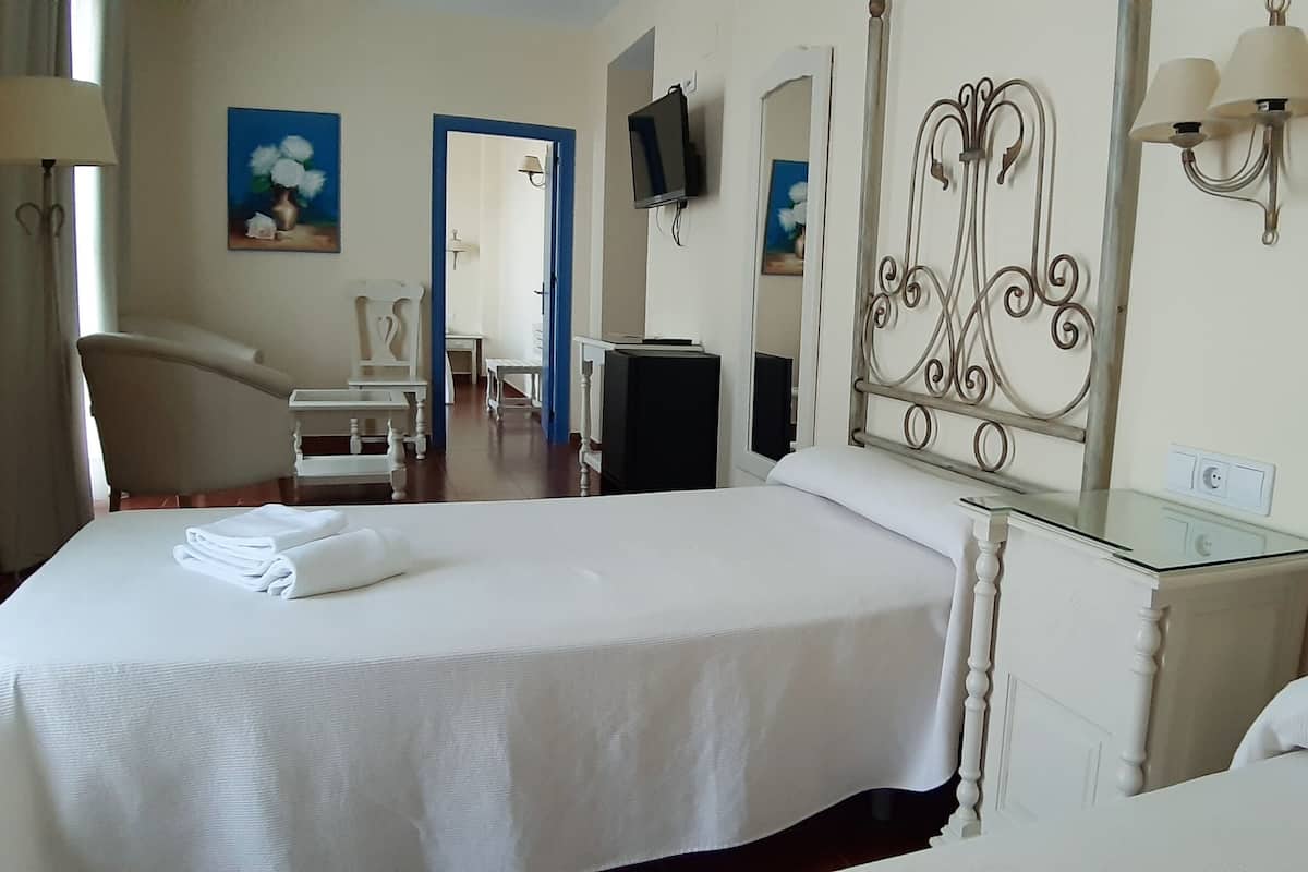 A hotel room with two beds, a TV, a desk, and a chair.