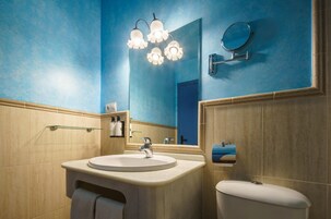 Un baño con lavamanos, espejo e inodoro.