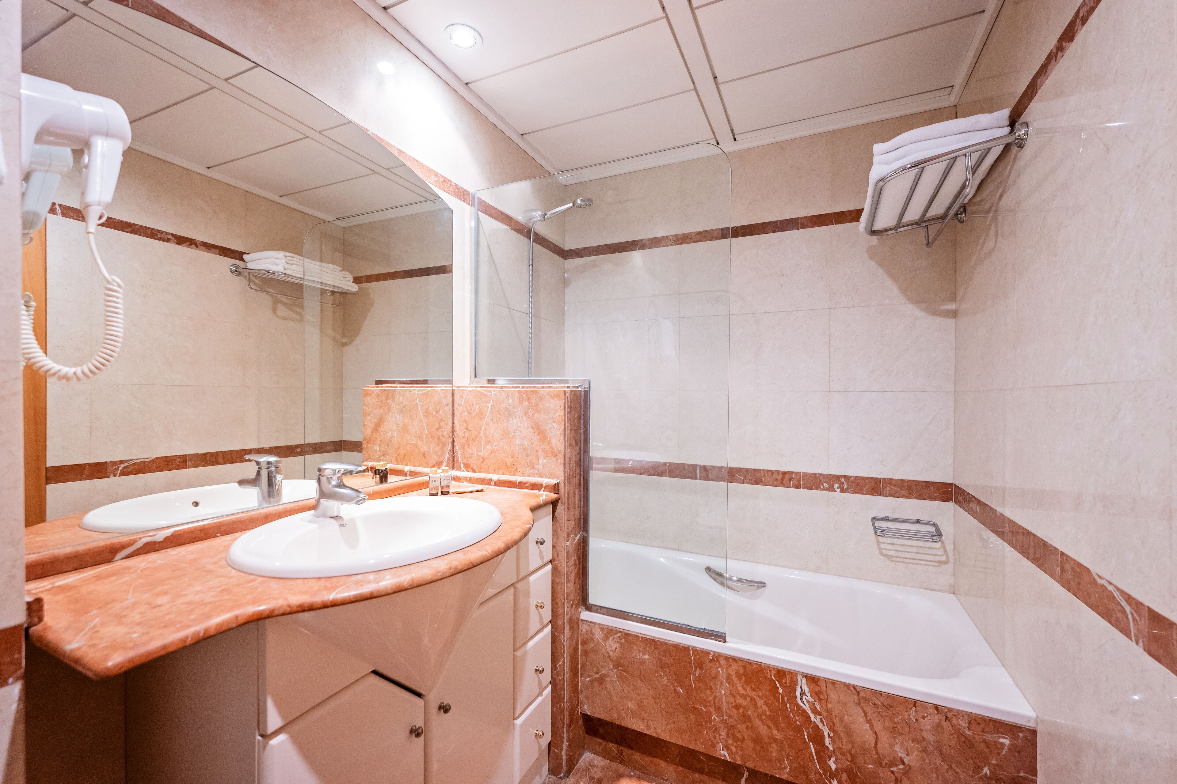 Un baño con dos lavamanos, una ducha y un secador de pelo.