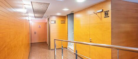A hallway with wooden walls, a metal railing, and a door at the end.
