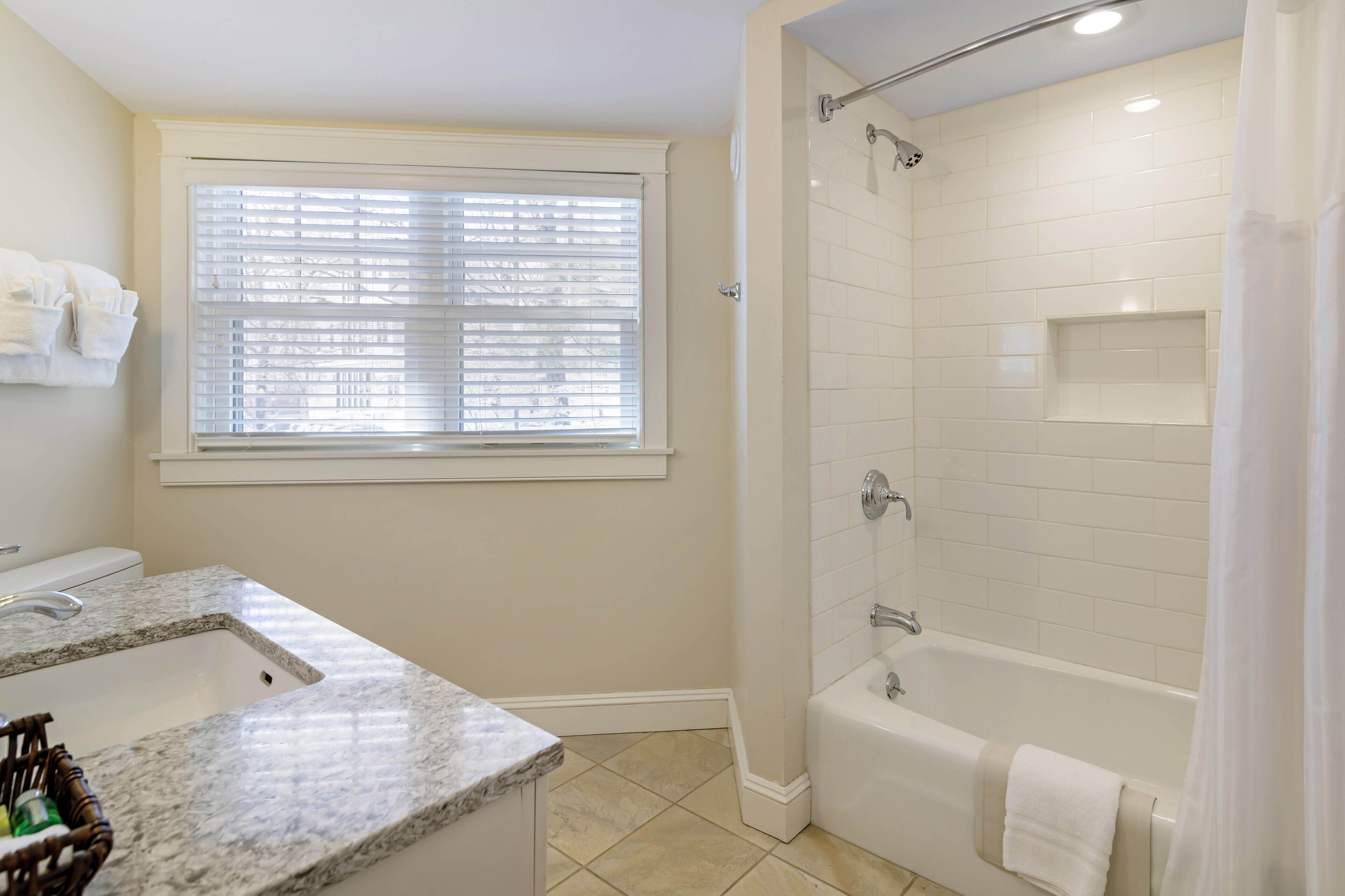A bathroom with a shower, a sink, and a window.