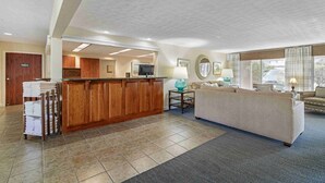 A hotel lobby with a reception desk, a sofa, a coffee table, and a tiled floor. - Juniper Hill Inn (Ogunquit)