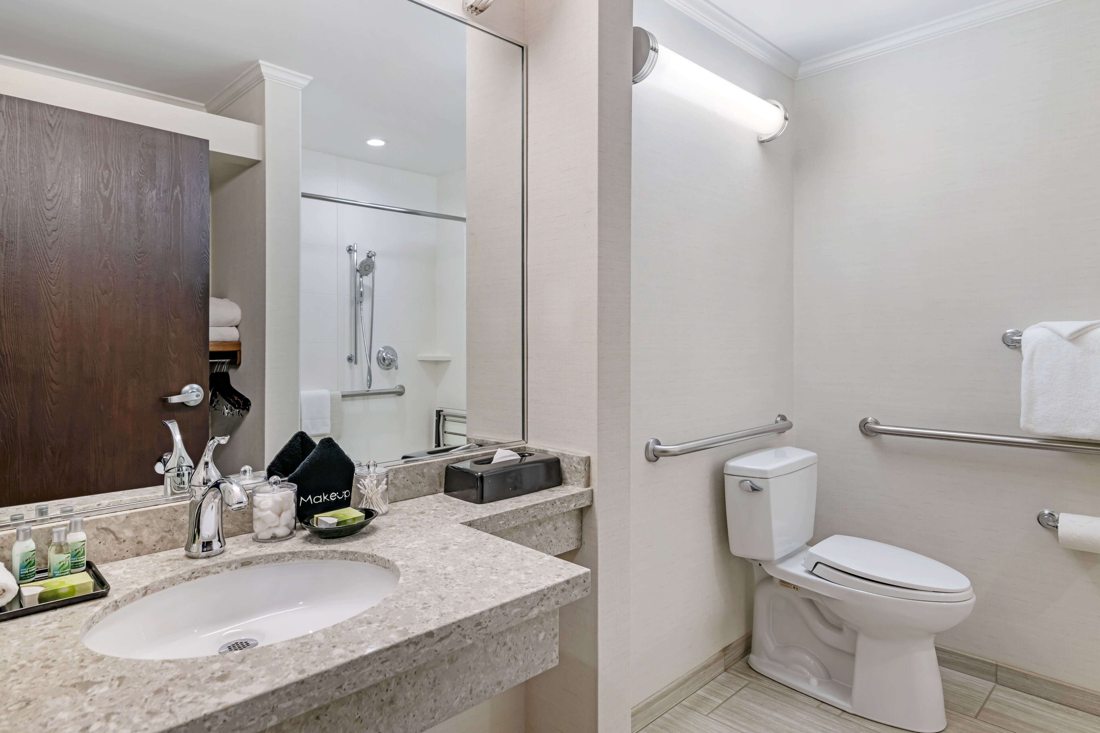 A modern bathroom with a sink, mirror, and toilet.