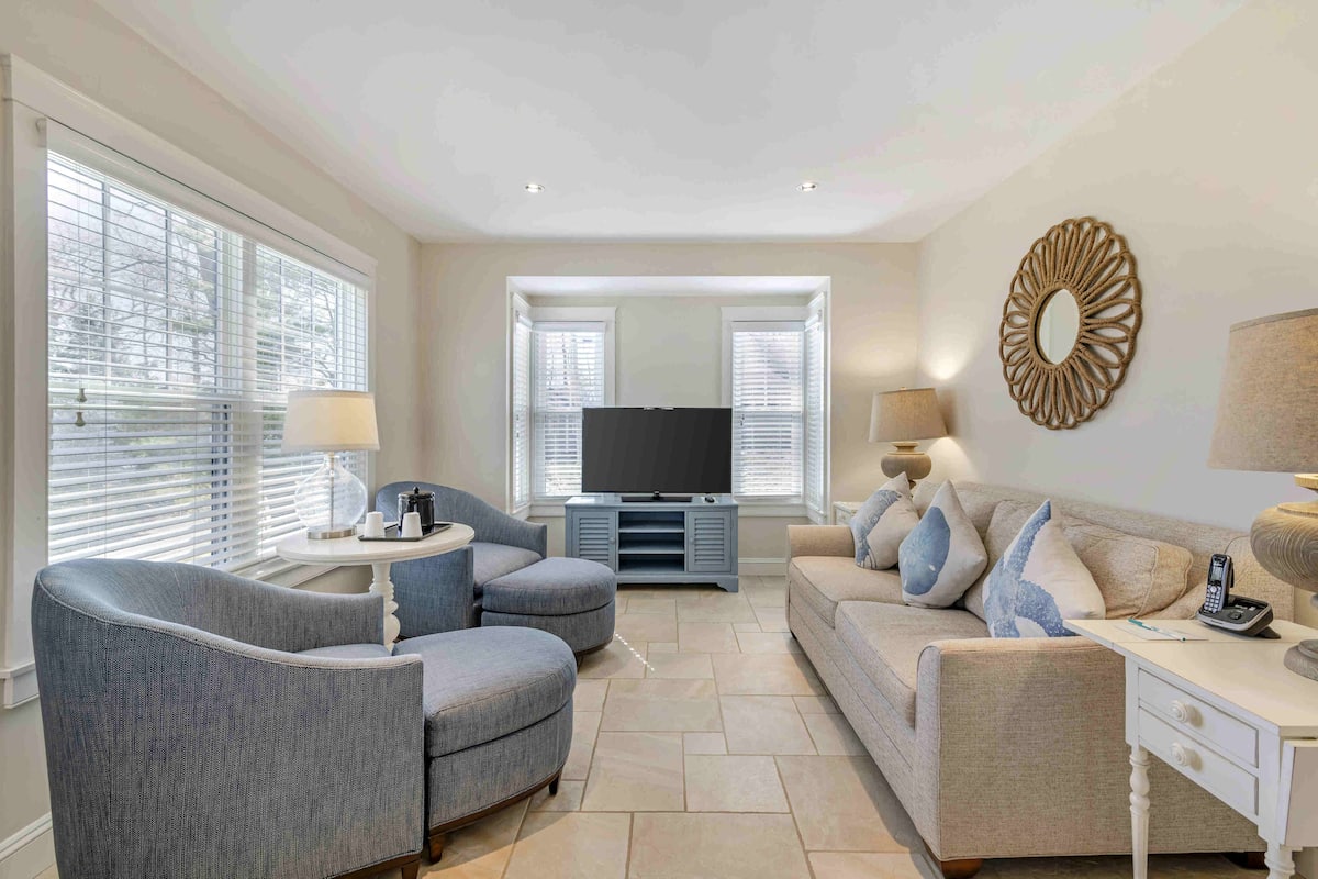 A living room with a TV, two sofas, a coffee table, and a lamp.
