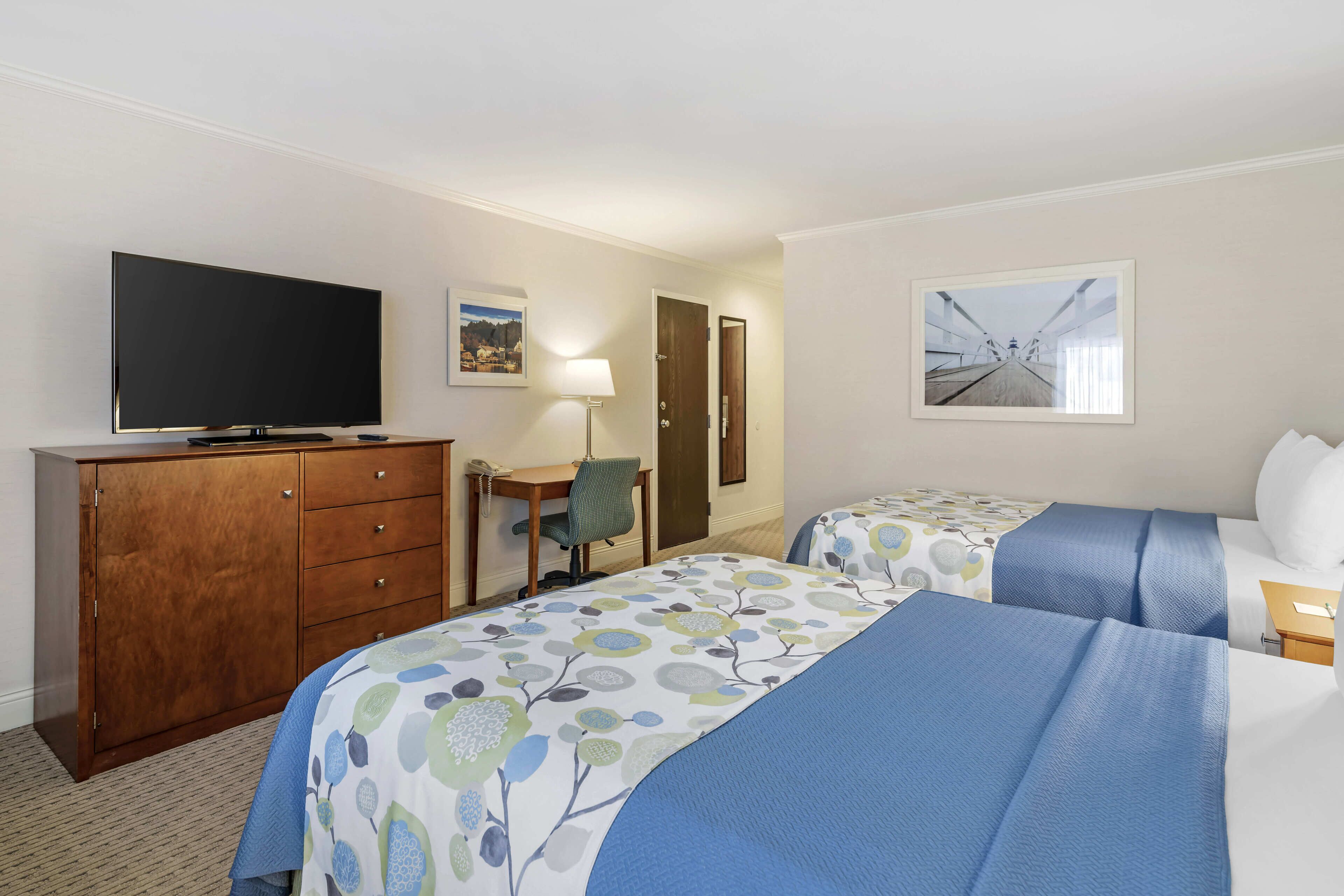 A hotel room with two beds, a TV, a desk, and a chair.
