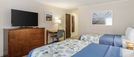 A hotel room with two beds, a TV, a desk, and a chair.
