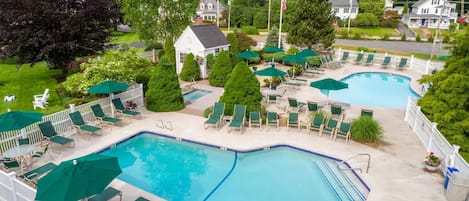 A swimming pool area with multiple pools, lounge chairs, and umbrellas.