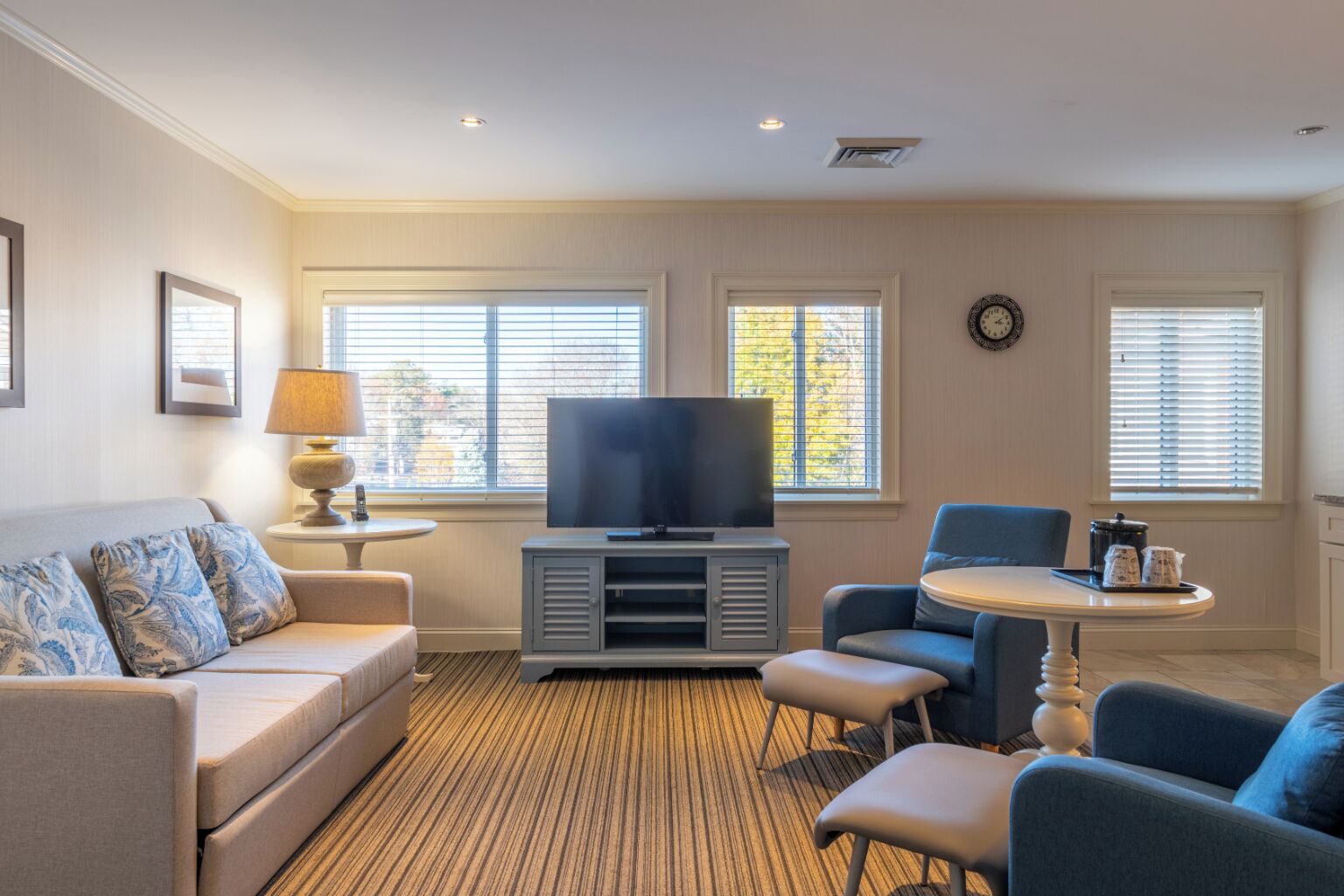 A living room with a sofa, a TV, a small table, and two chairs.
